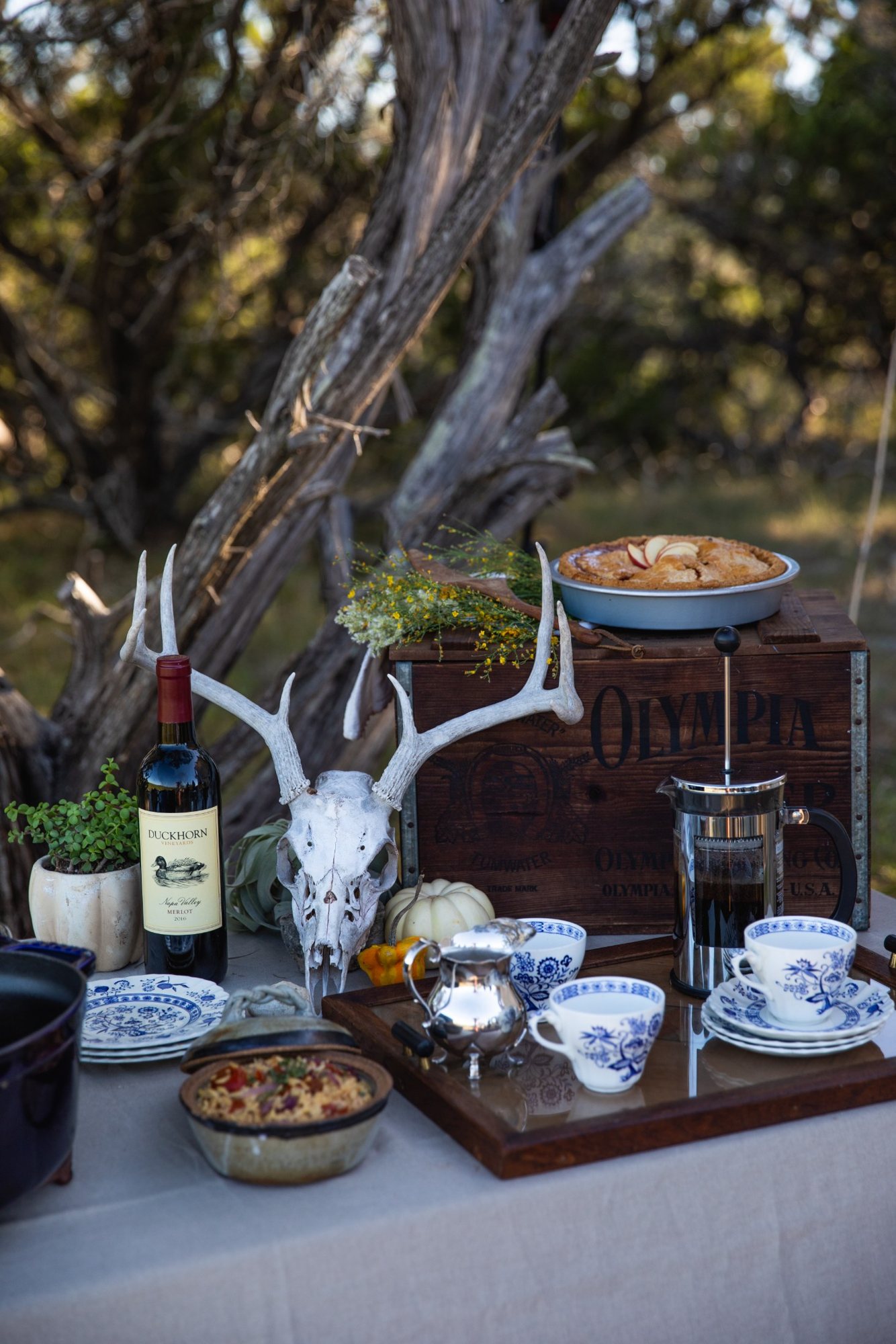 An outdoor table set with wine for a wild game dinner
